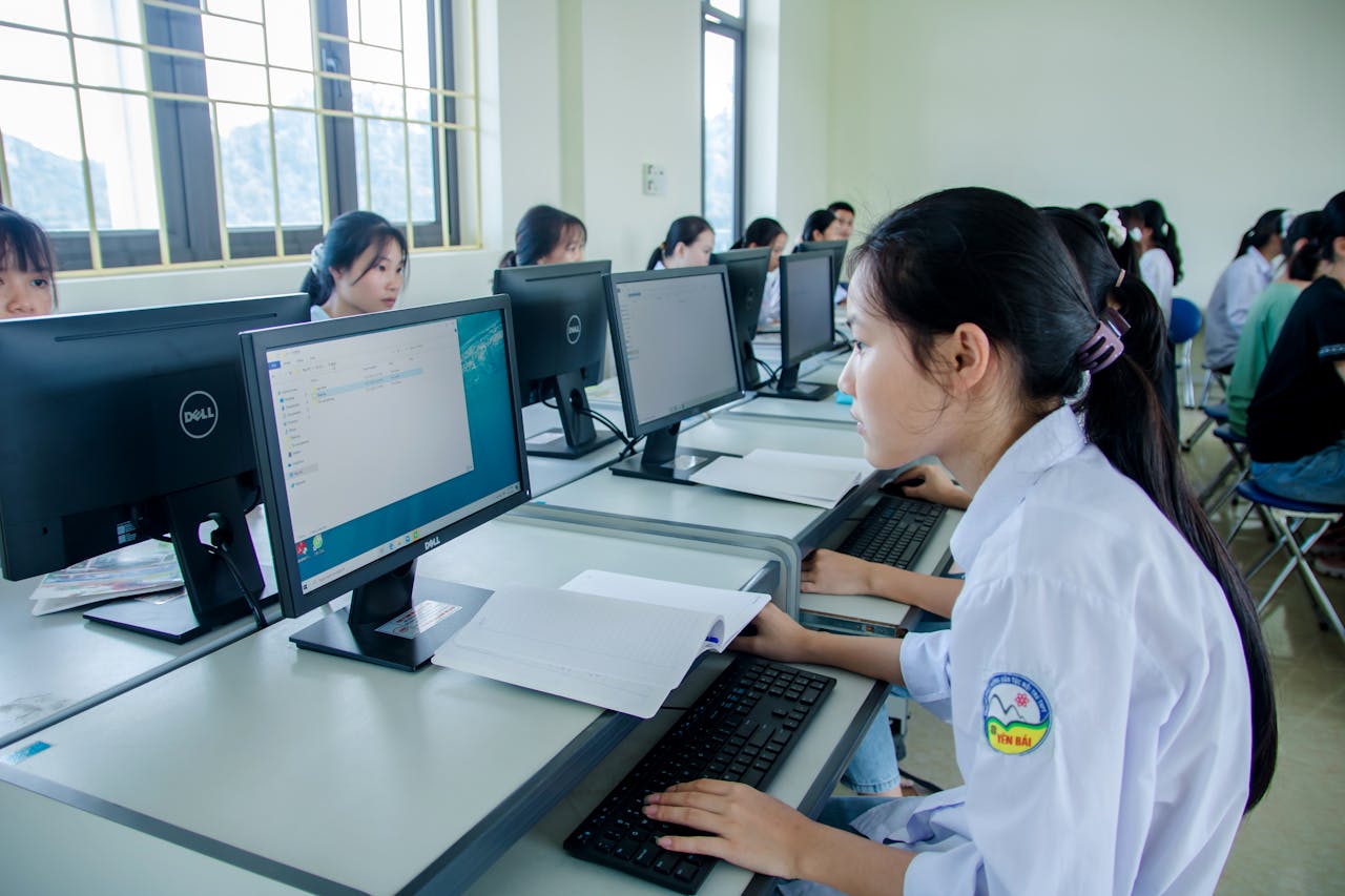 Group of Asian students working together in a computer lab focused on teamwork and technology.